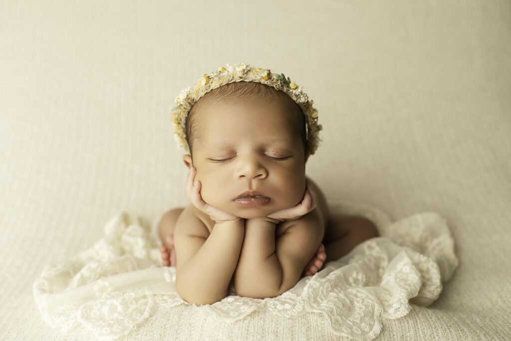 Newborn girl peacefully posed on a neutral backdrop, capturing her delicate features with soft, simple styling in the studio