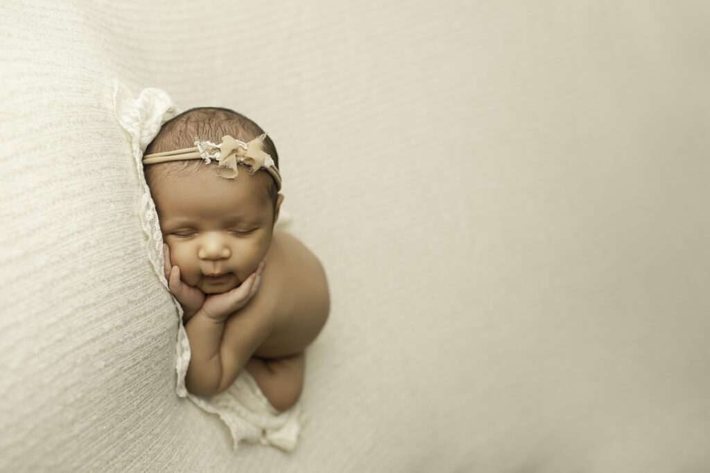 Sweet newborn girl lying on a neutral backdrop, elegantly posed with minimal props, highlighting her natural beauty