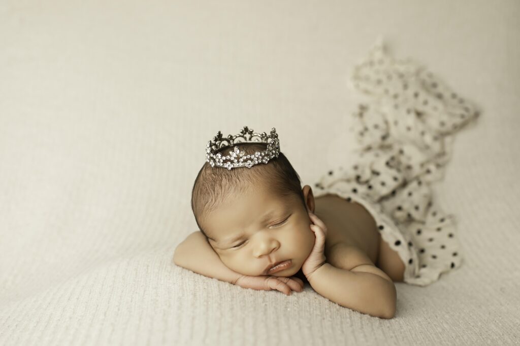 Simple and serene newborn girl portrait, lying on a neutral backdrop with soft lighting in the studio with tierra