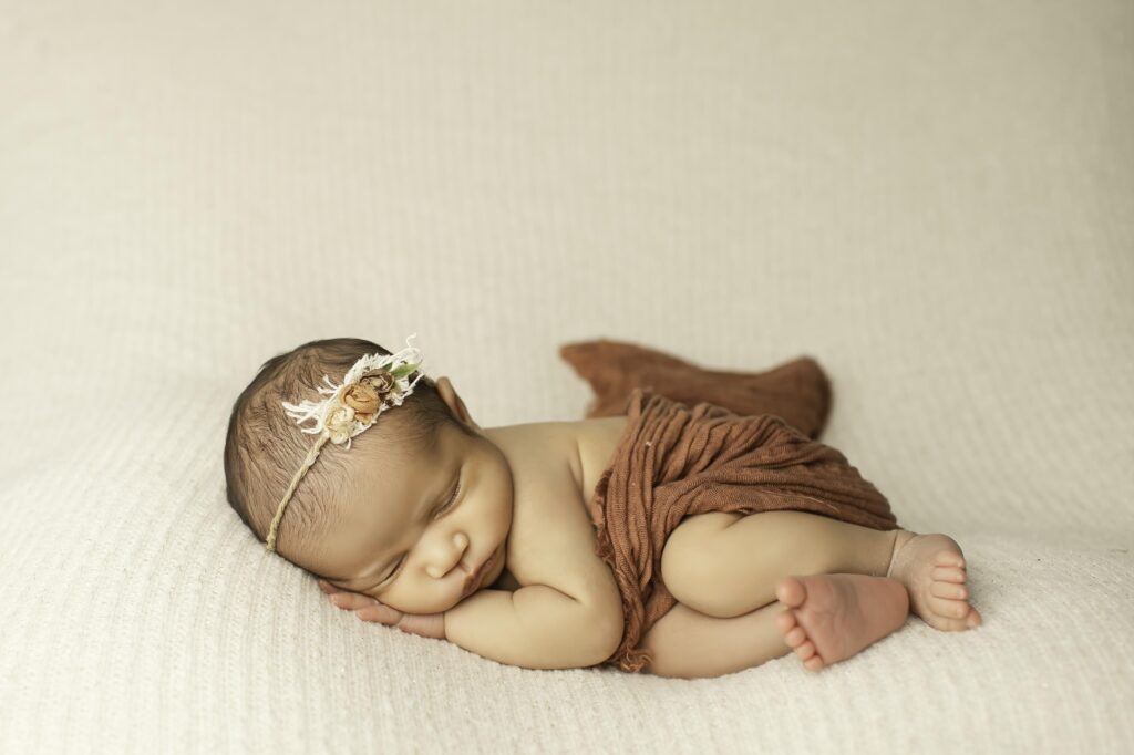 Newborn girl lying peacefully in a simple pose, swaddled in soft fabric