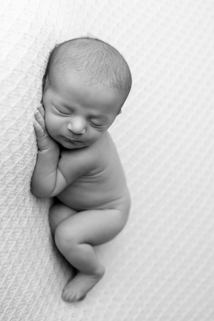 Newborn baby boy with a calm expression, lying on a soft surface