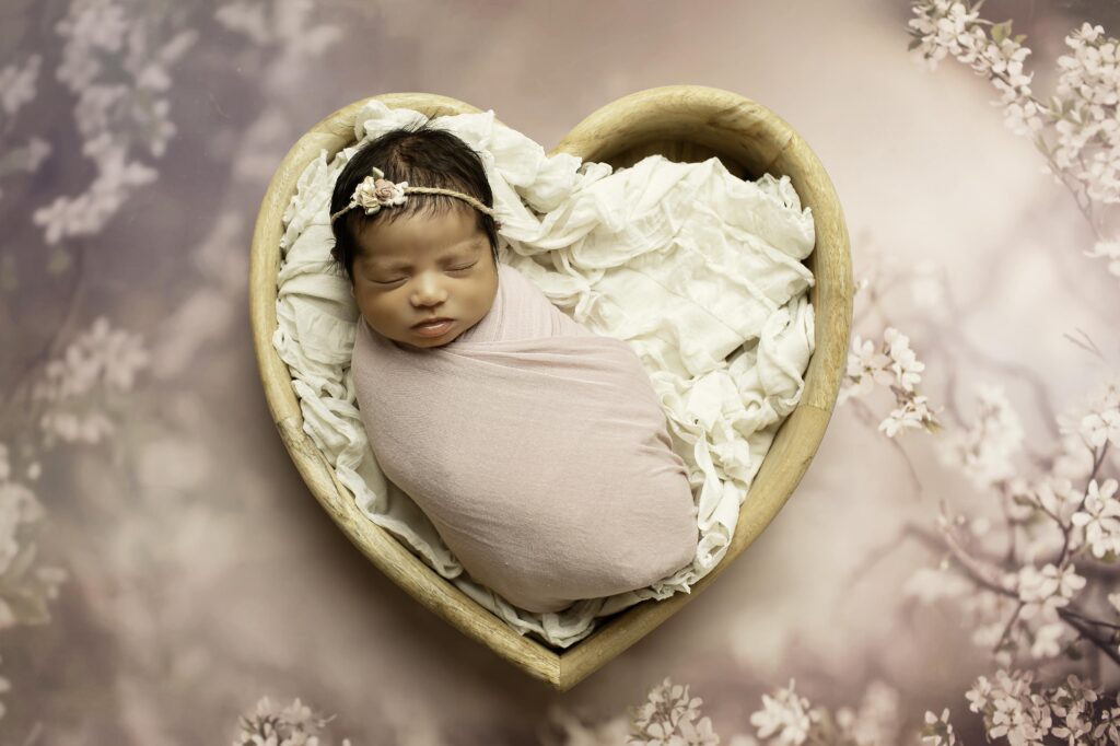 A newborn girl peacefully sleeps in a cozy blanket in a Fort Worth studio, her delicate features captured in a soft and timeless portrait