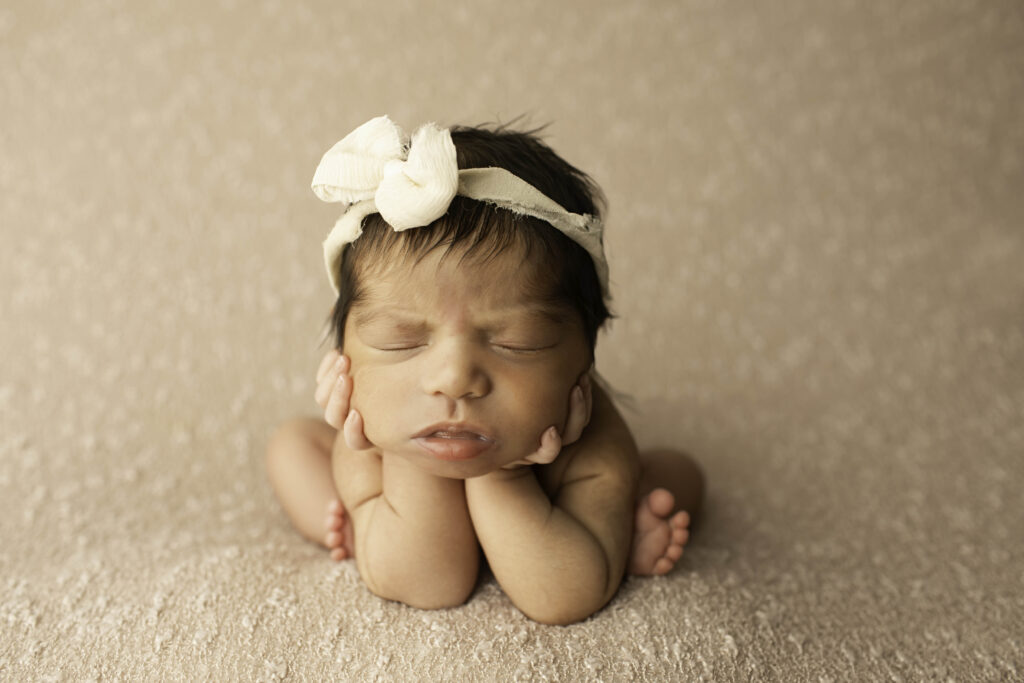 A newborn girl is swaddled in soft fabric, gently posed in a Fort Worth area studio, creating a timeless image of her delicate beauty