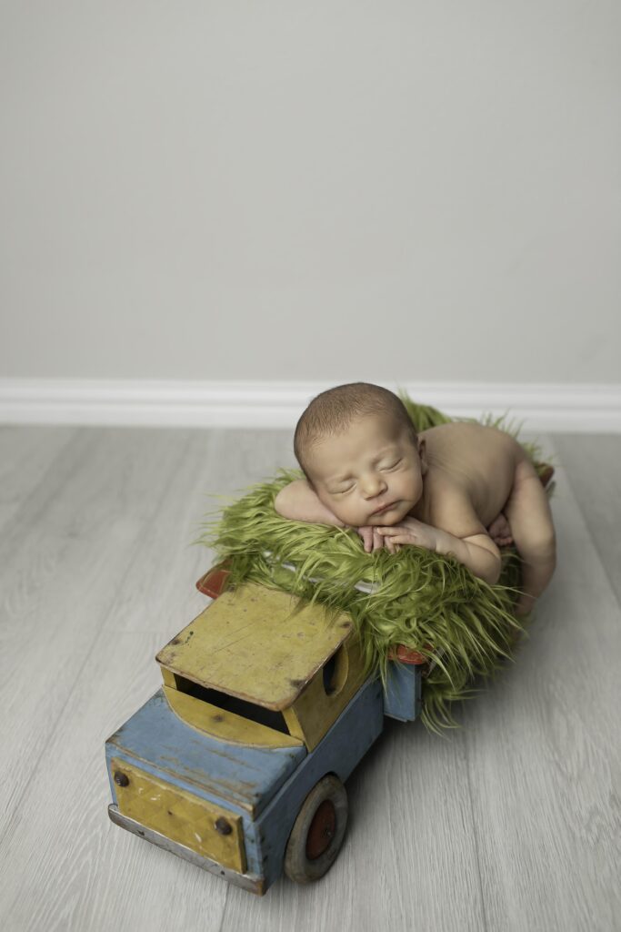 Newborn baby boy curled up in a cozy studio prop