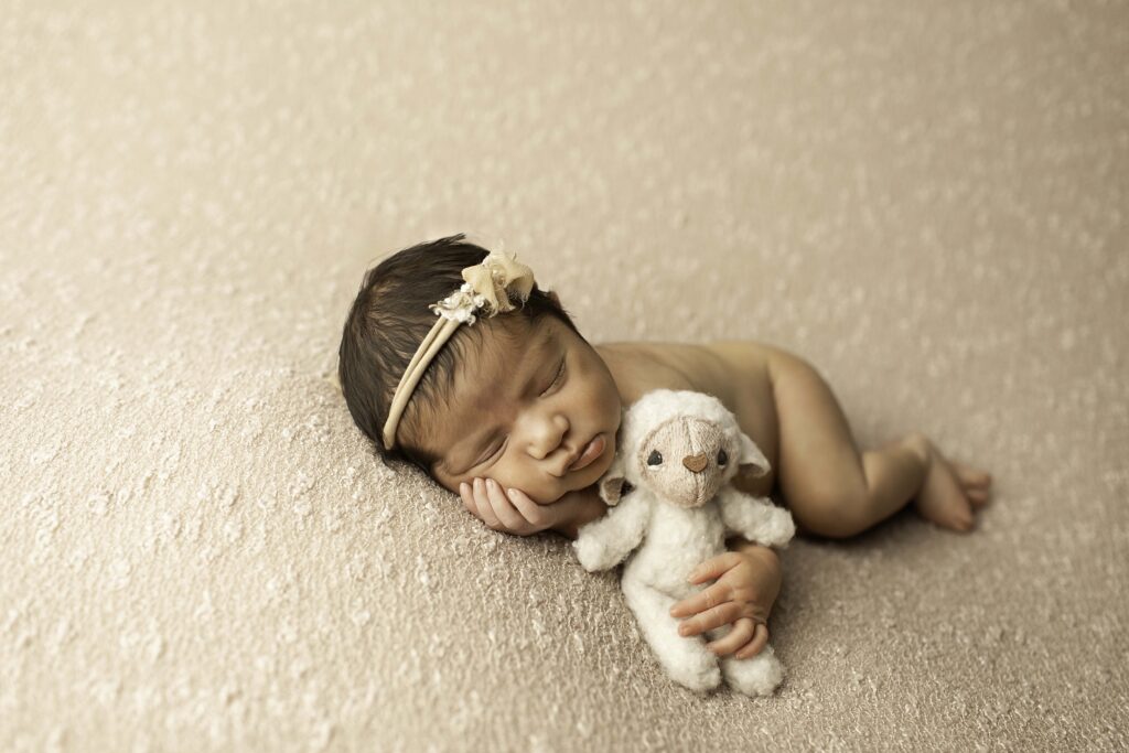 In a cozy Fort Worth studio, a newborn girl rests peacefully on a soft surface, her sweet face captured in a timeless, heartwarming moment