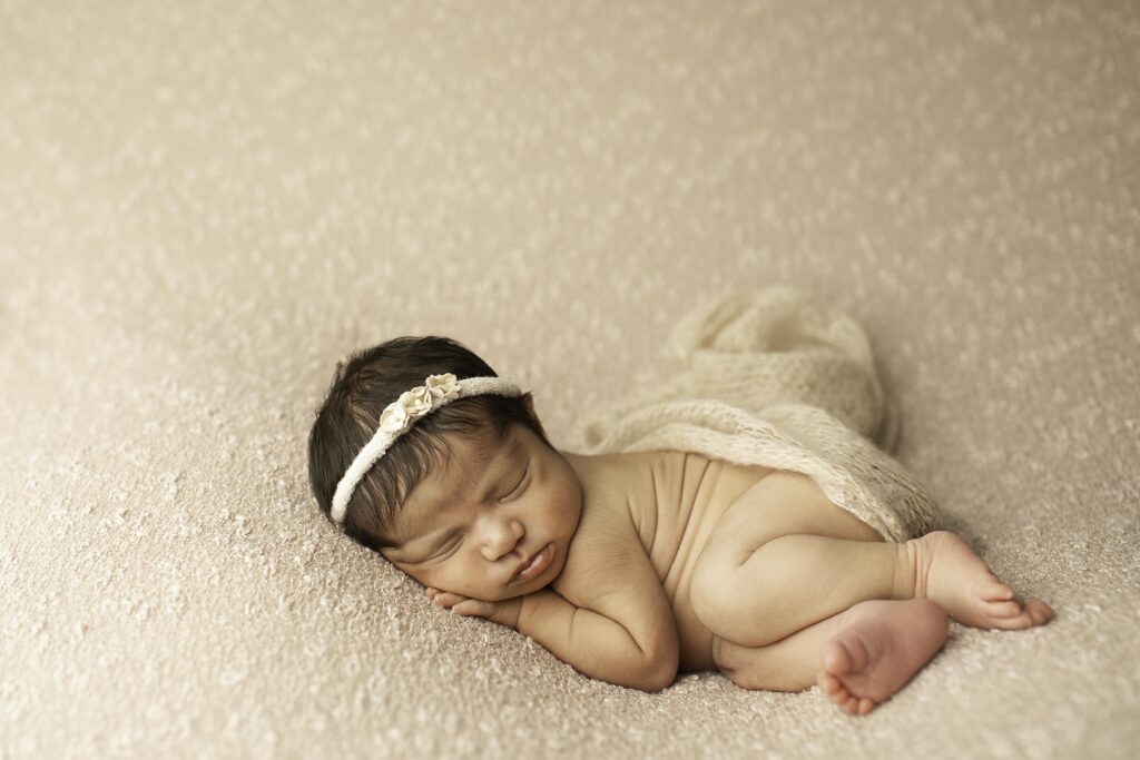 A newborn girl peacefully sleeps on a soft blanket, her tiny features captured in a serene and simple Fort Worth studio shot