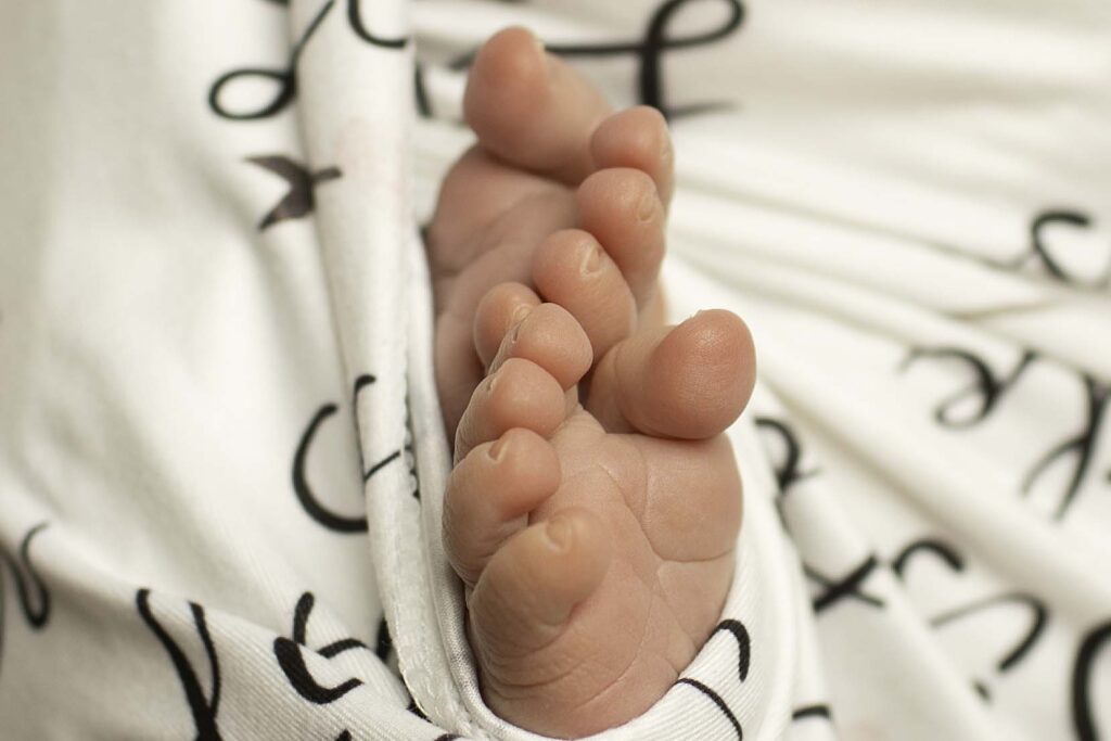 A close-up shot of a newborn's tiny, delicate toes, nestled softly in a cozy blanket, capturing the innocence and beauty of their first moments