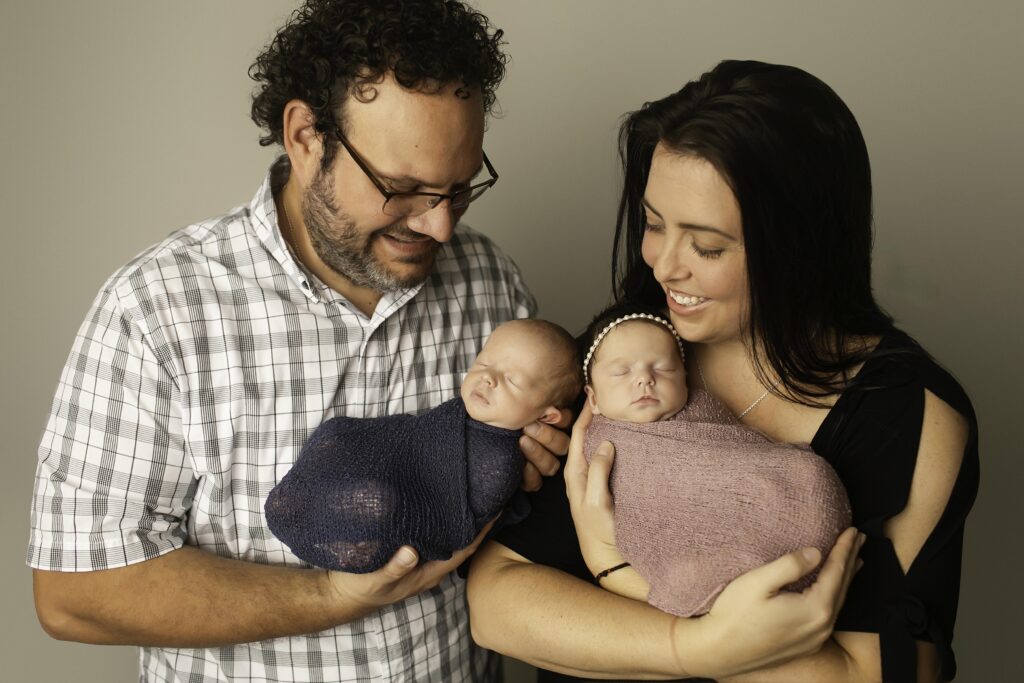 Adorable twin babies snuggled together during their photoshoot.