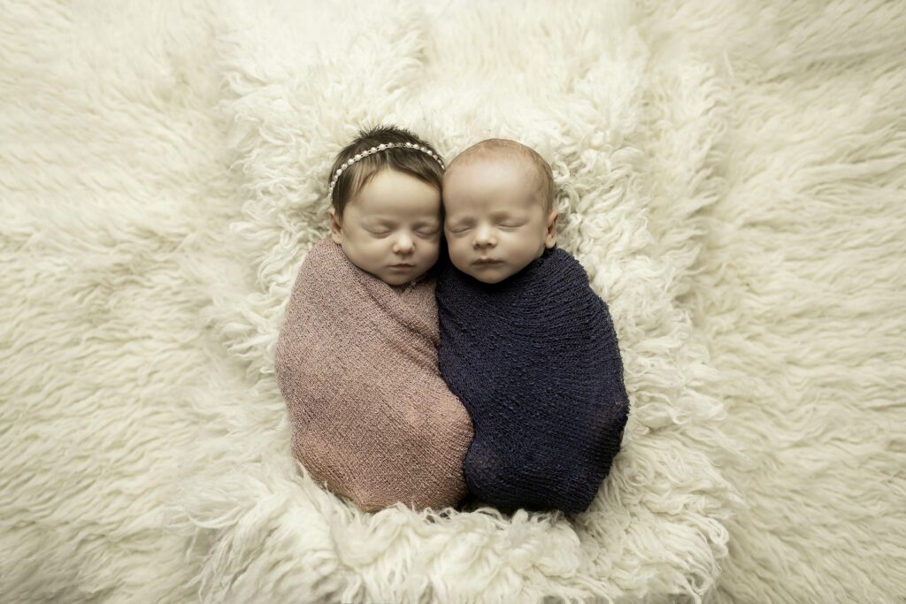 Twin newborn babies wrapped in soft, fluffy swaddles during a photoshoot