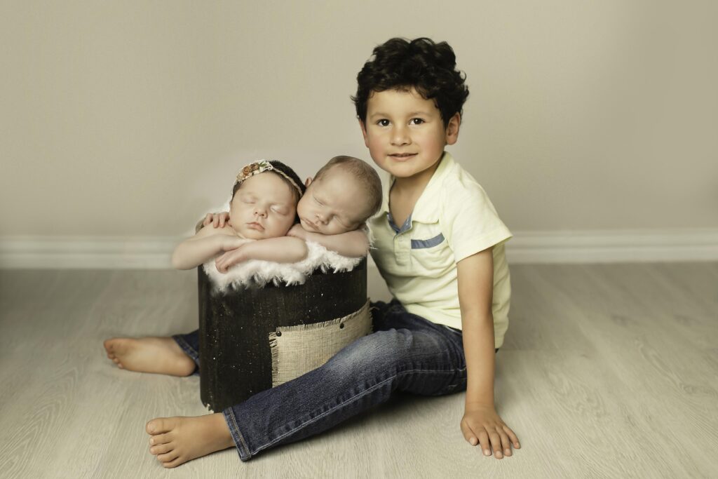 Sweet photo of big brother cuddling with his newborn twin brothers/sisters