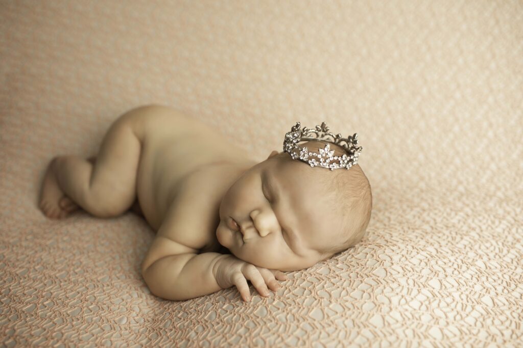 The newborn’s round, cherubic cheeks stand out as they lie on a fluffy surface, exuding warmth and serenity in their cozy setting