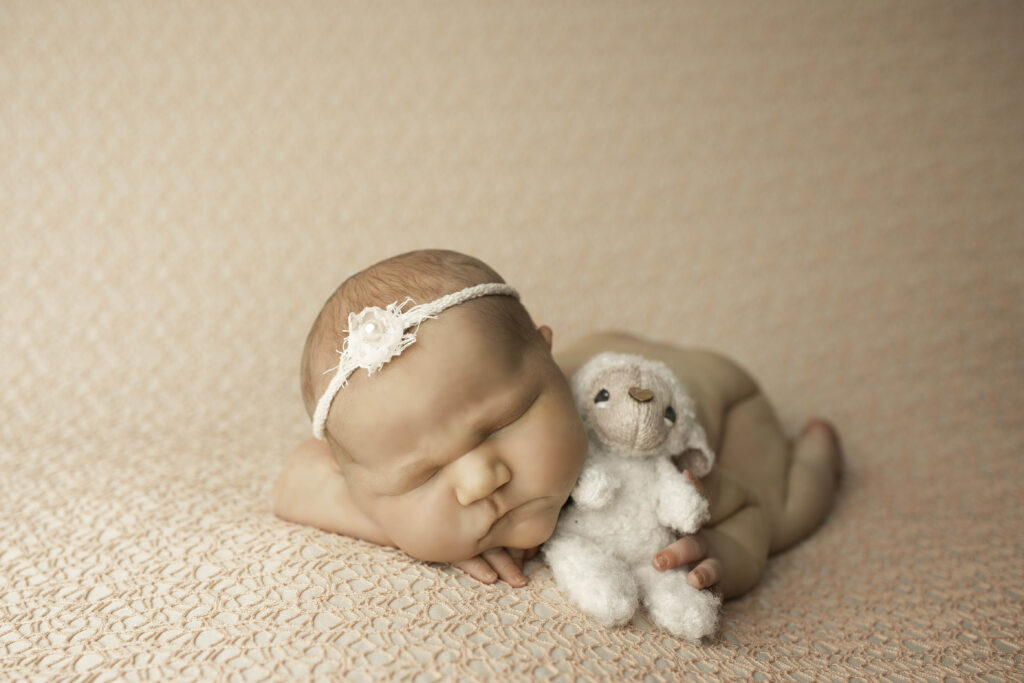 A newborn with irresistibly chunky cheeks, lies peacefully on a cushioned surface, capturing the perfect moment of calm.