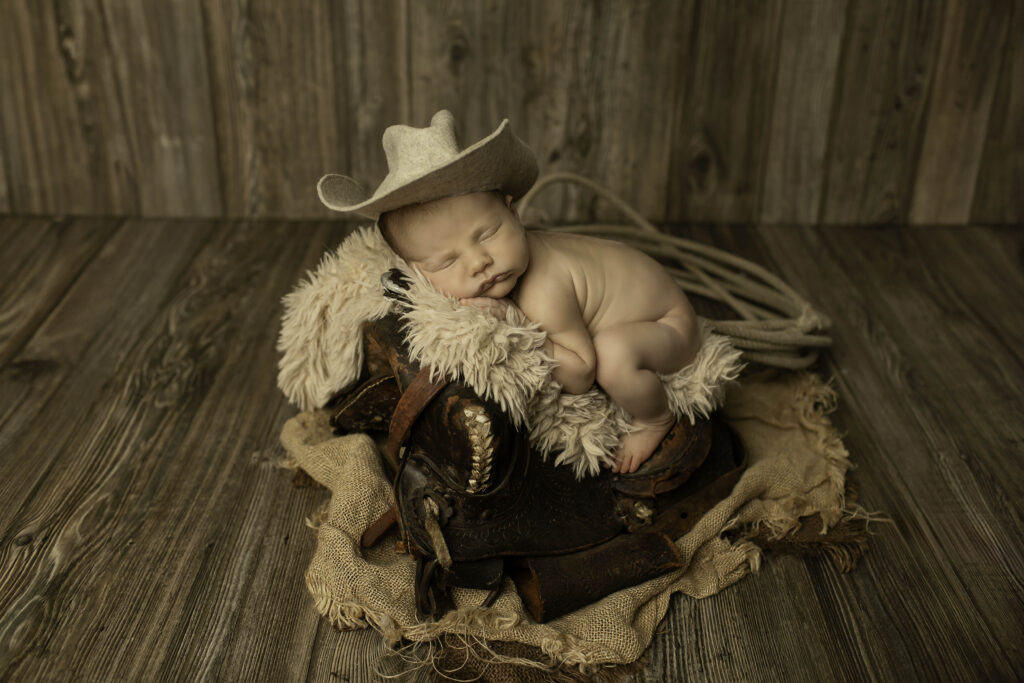 Newborn baby boy peacefully asleep, surrounded by fluffy blankets and soft props in a Chunky Monkey session