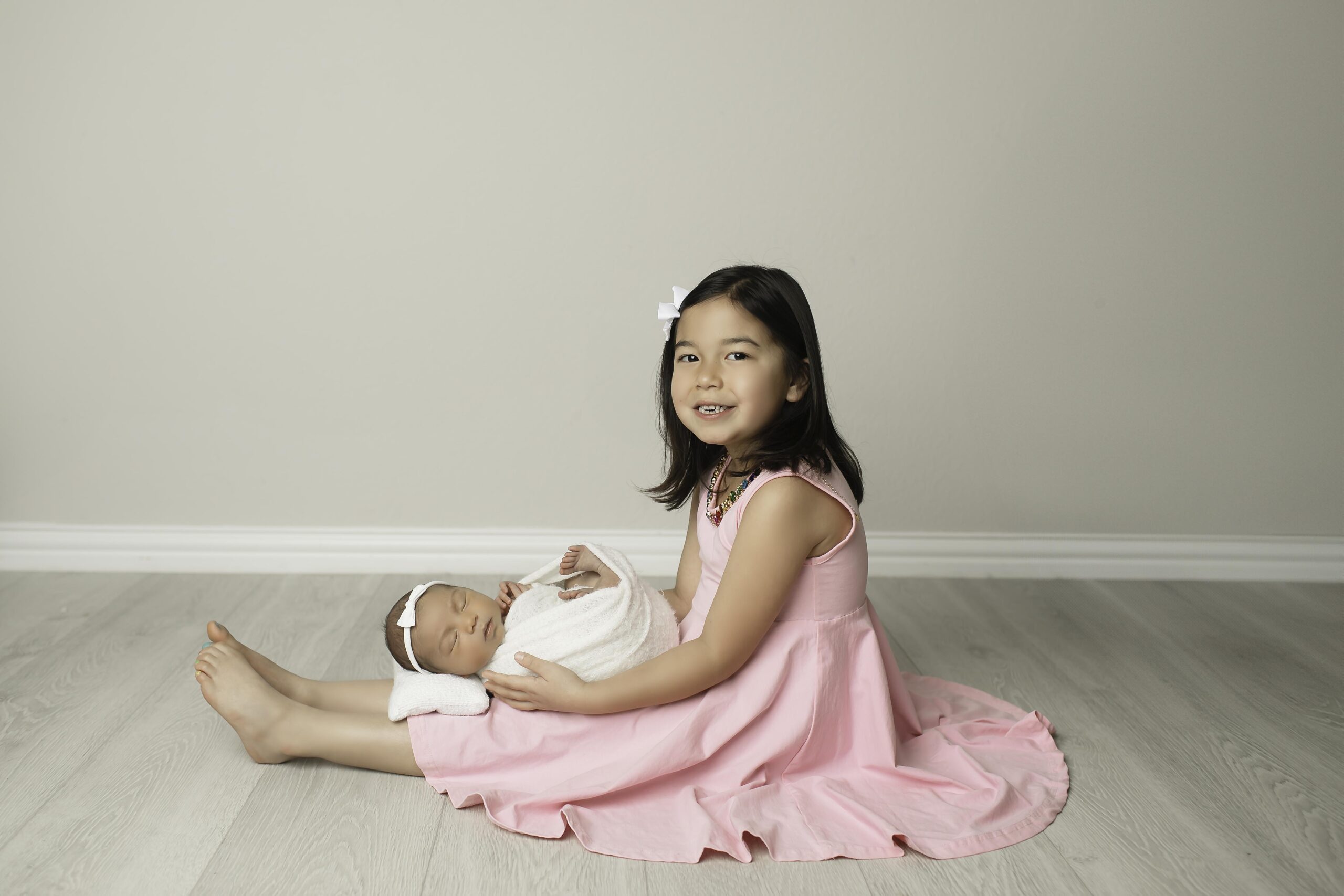 Big sister lovingly cradling her newborn baby sister, captured in a beautiful family moment during a Chunky Monkey Photography session