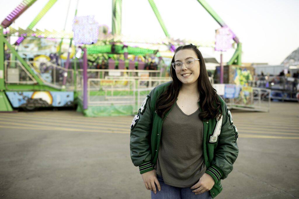 Senior girl holding a prize and laughing near the ring toss game at the Stockshow carnival.