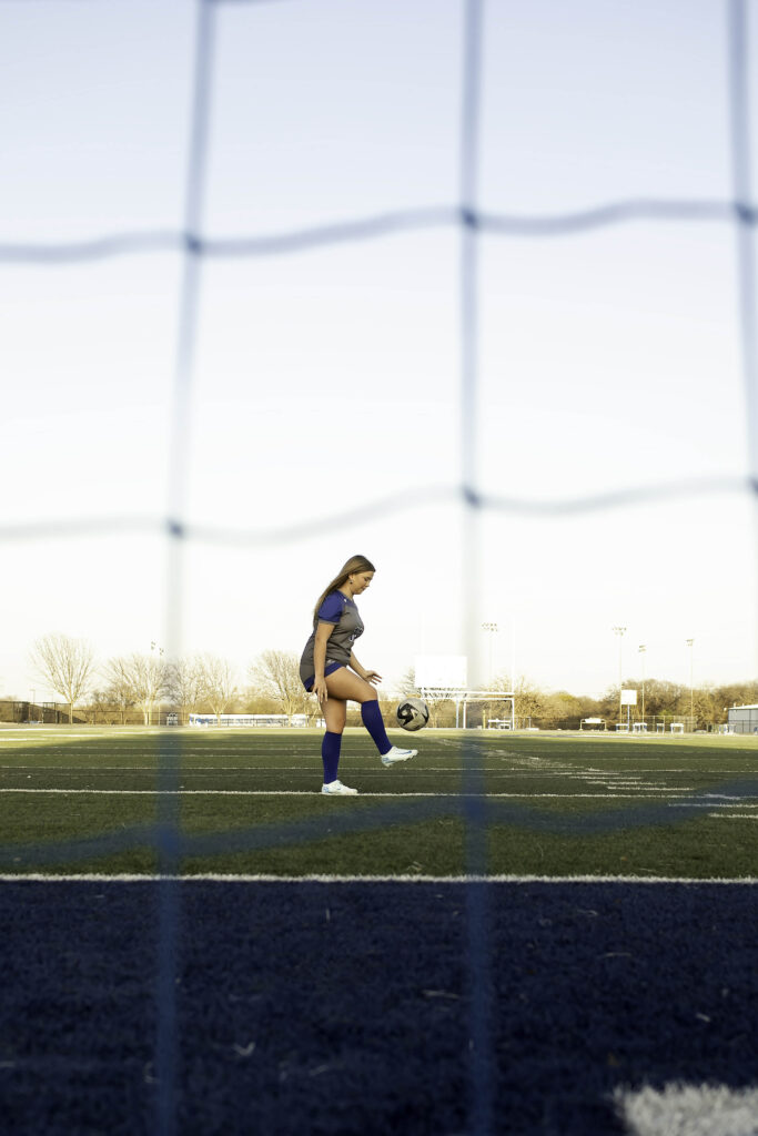 High school soccer player dribbling the ball across the field, eyes focused ahead, showcasing agility and control.