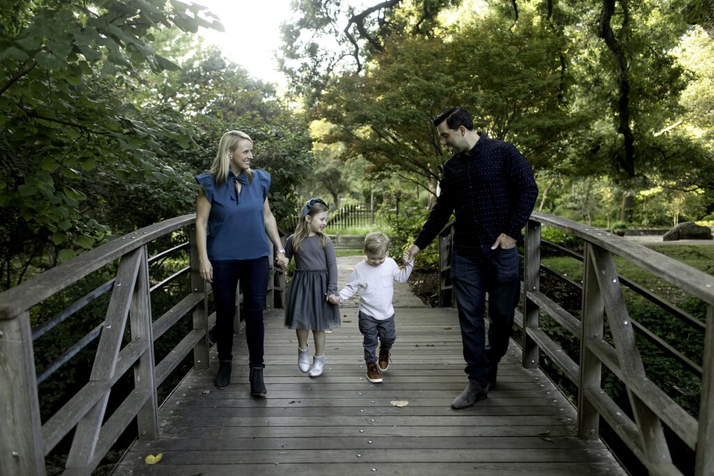 Family of four walking hand-in-hand down a flower-lined path at the Fort Worth Botanical Gardens