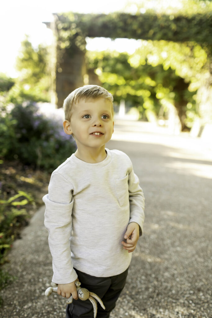 Young boy standing confidently on a garden path, surrounded by vibrant flowers