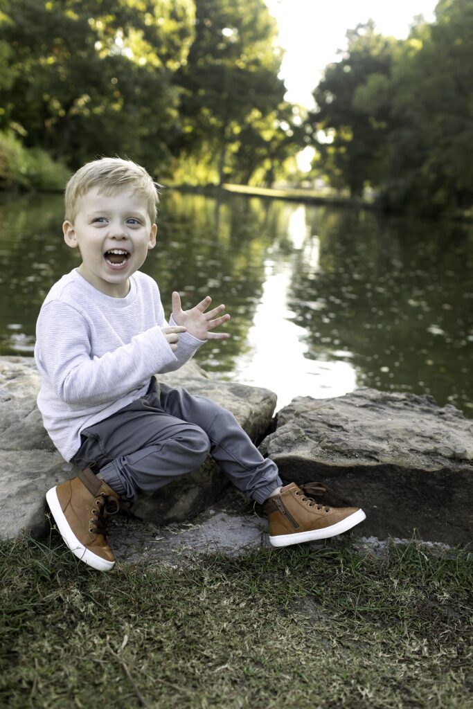 Brother sitting on a rock surrounded by blooms, looking thoughtfully at the camera