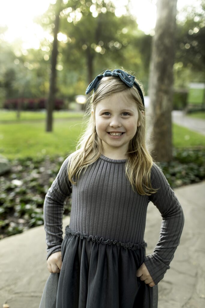 Young girl twirling in a floral dress on a garden path