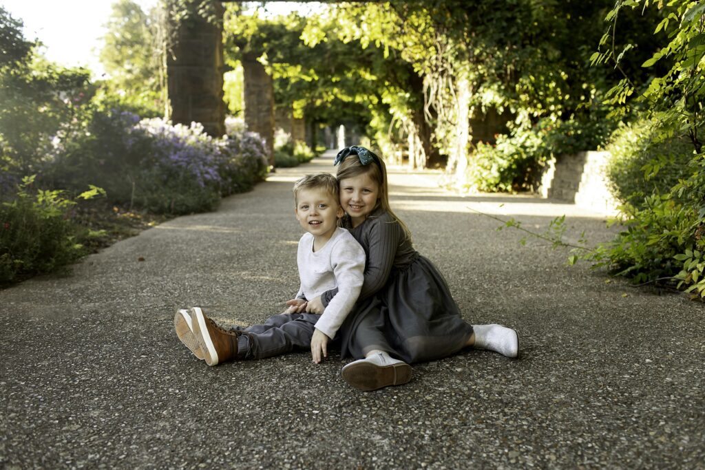 Brother and sister laughing together while sitting on a stone wall