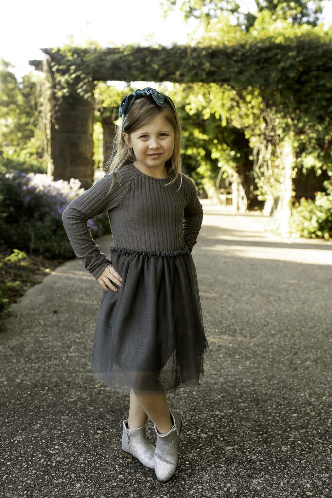 Sister standing under a tree, hands clasped in front of her with a soft smile