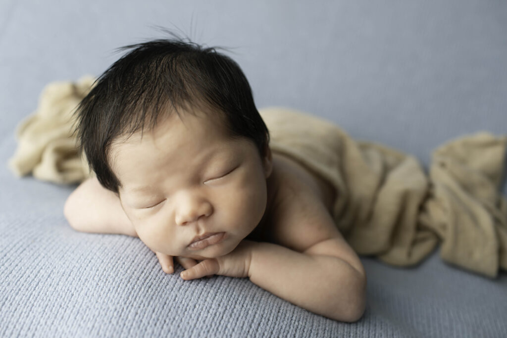 Brother lying on his stomach on a blanket, head resting on his hands