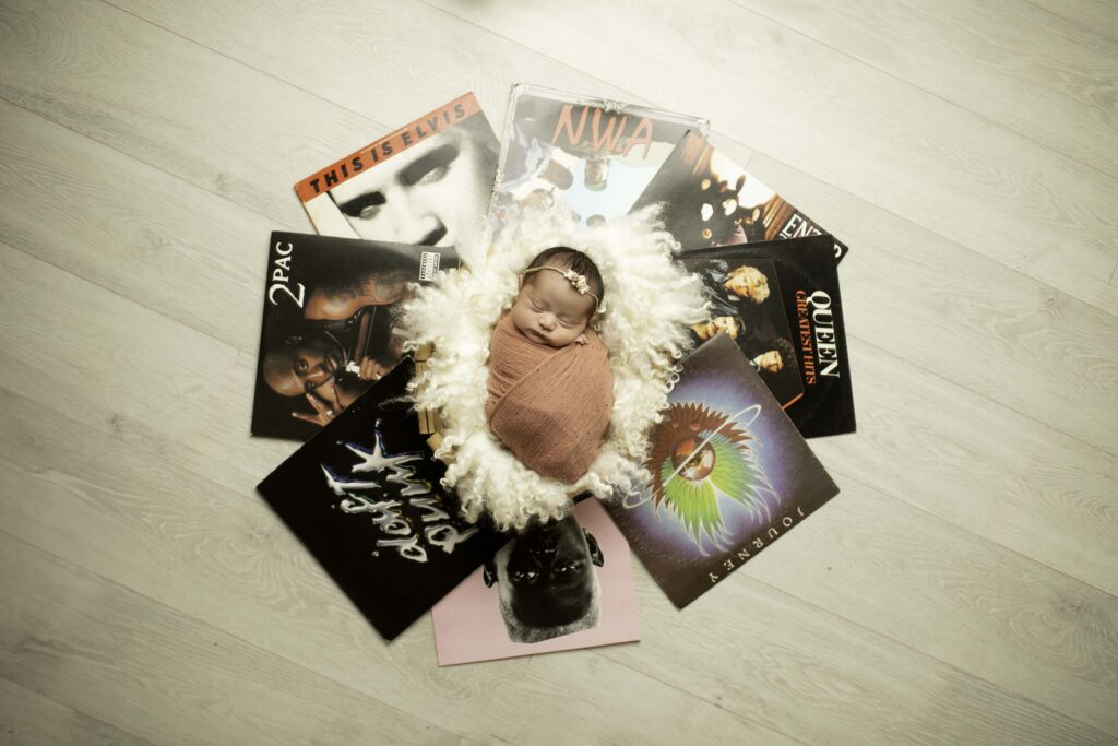 Newborn swaddled and nestled among vintage records, creating a timeless and cozy atmosphere.