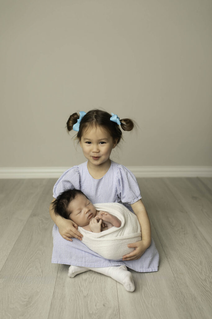 big sister holding newborn boy 